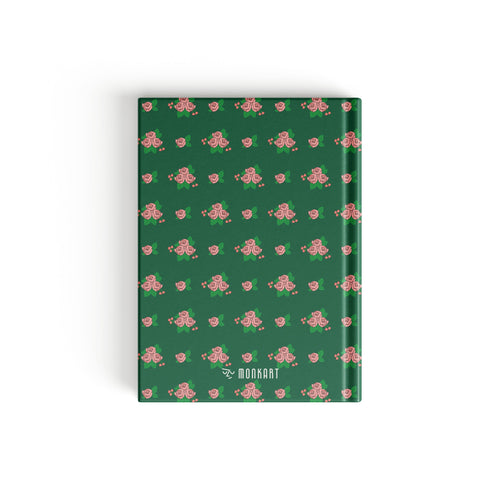 A hardcover notebook with a dark green cover featuring a repeating pattern of pink roses and green leaves.