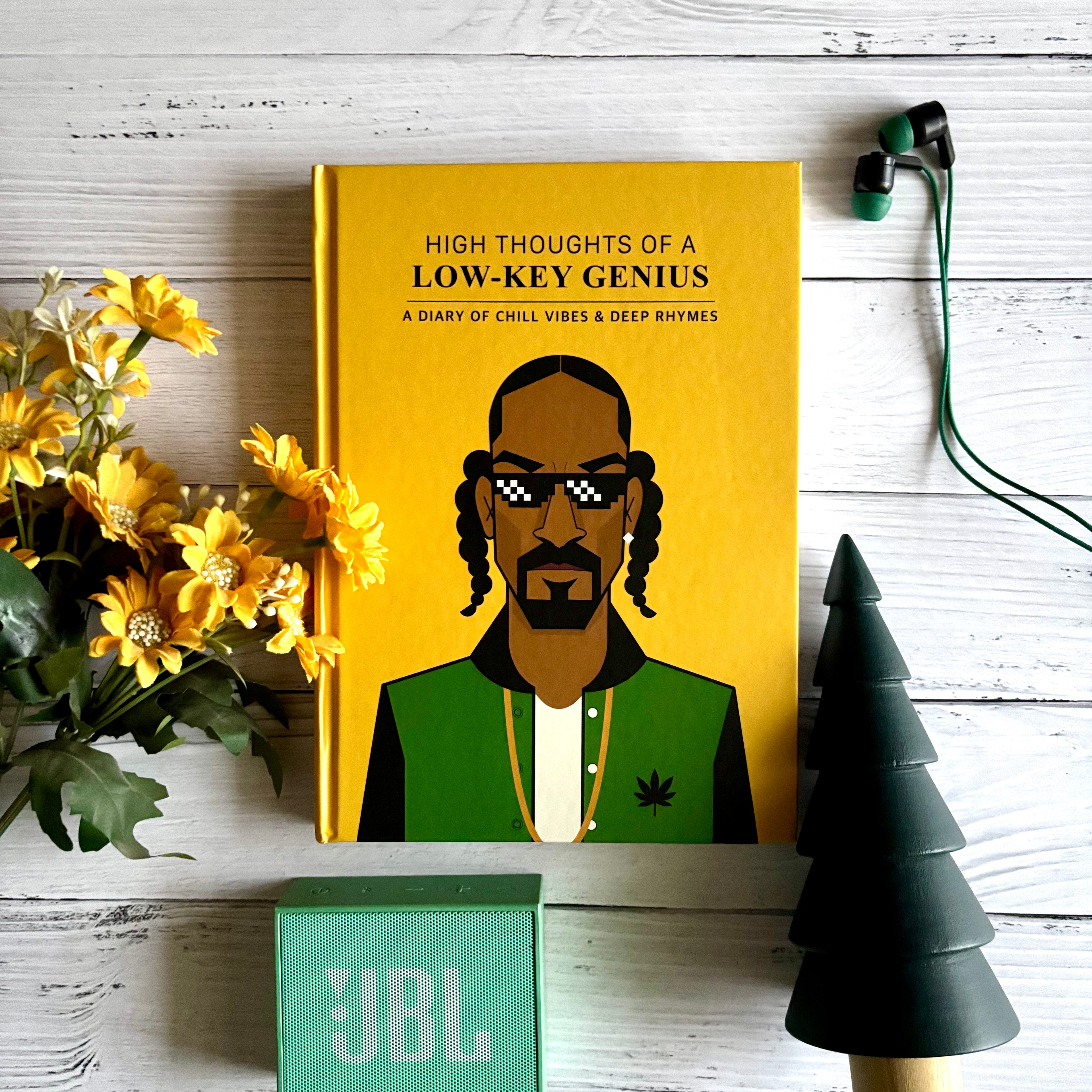 Snoop Dogg notebook titled 'High Thoughts of a Low-Key Genius' with a person's illustration on a yellow background, surrounded by flowers and a JBL speaker. Designed by Monkart.